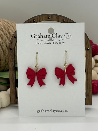 Red bow earrings on a 'Graham Clay Co' card with decorative background