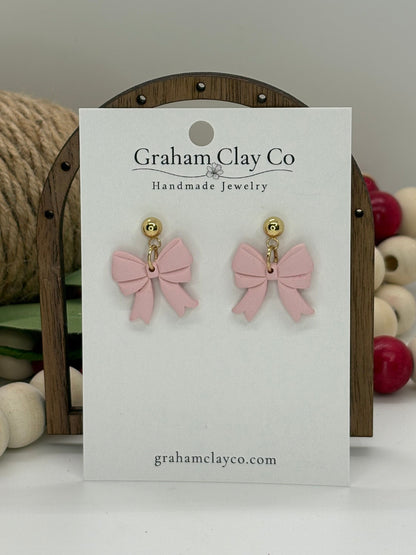 Pink bow earrings on a branded card with decorative background